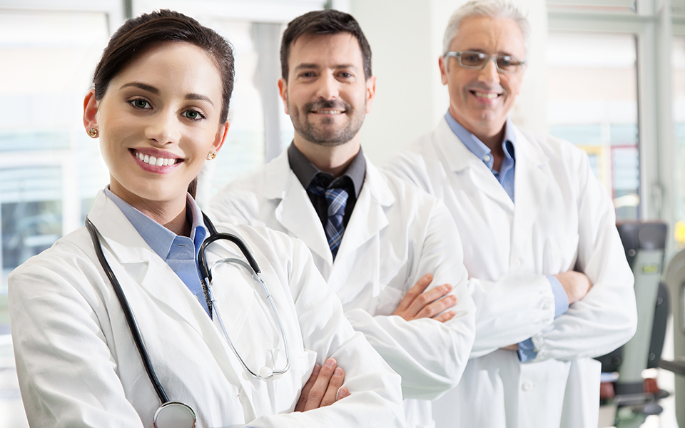 Three doctors standing, smiling, arms crossed