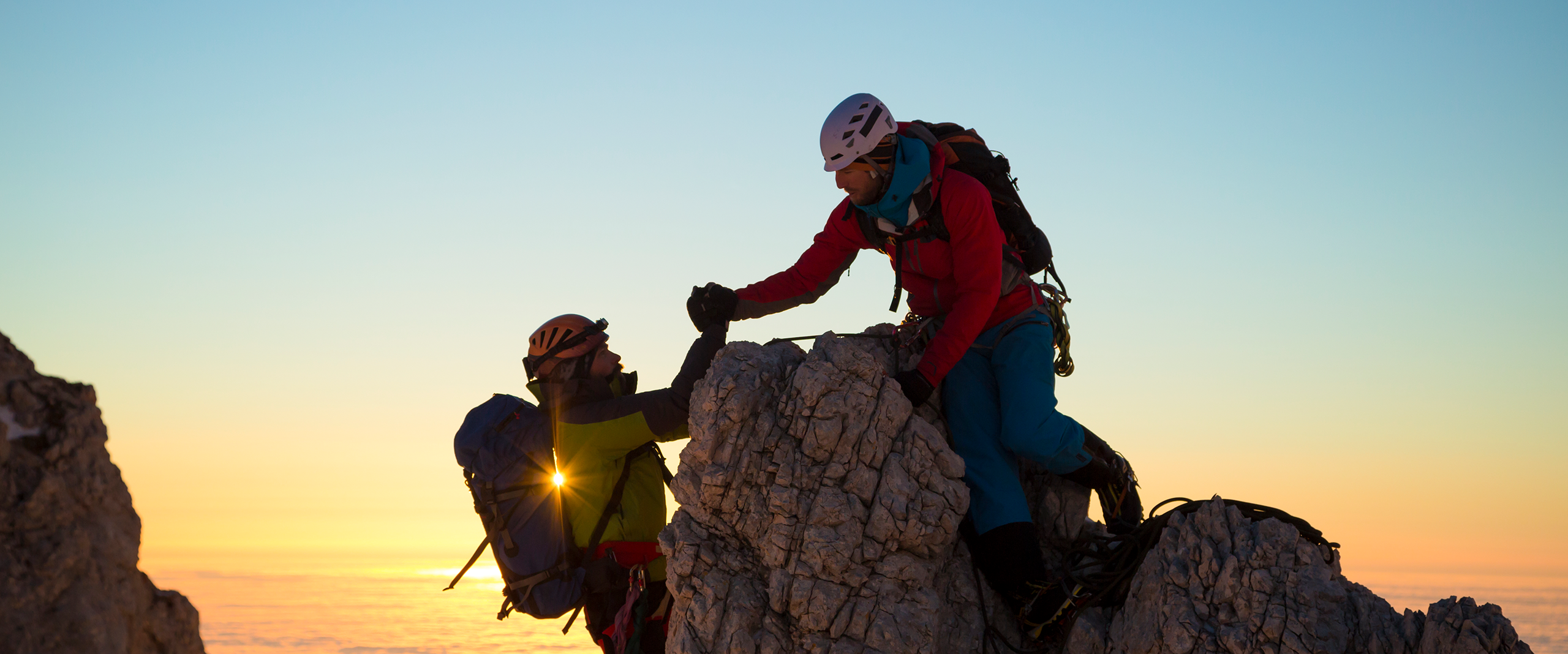 Cover of the 2024 OREF Annual Report Two climbers are at the crest of a rock. The one on top helps the other up.